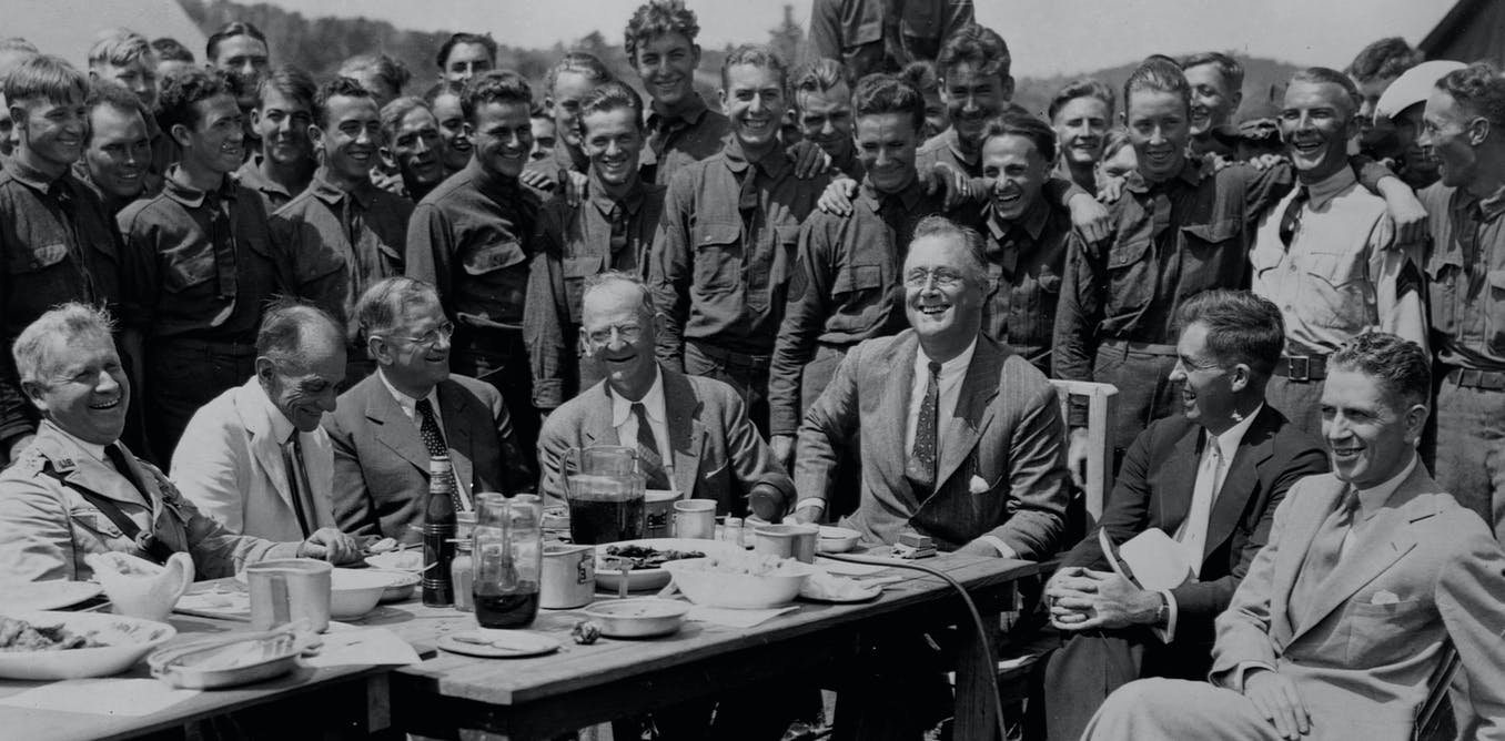Black and white historic photo of President Franklin D. Roosevelt and a few dozen members of the Civilian Conservation Corps in 1933.