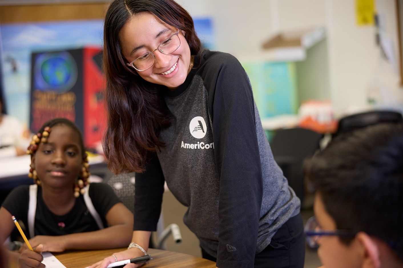 An Americorps member chats with students in a classroom.